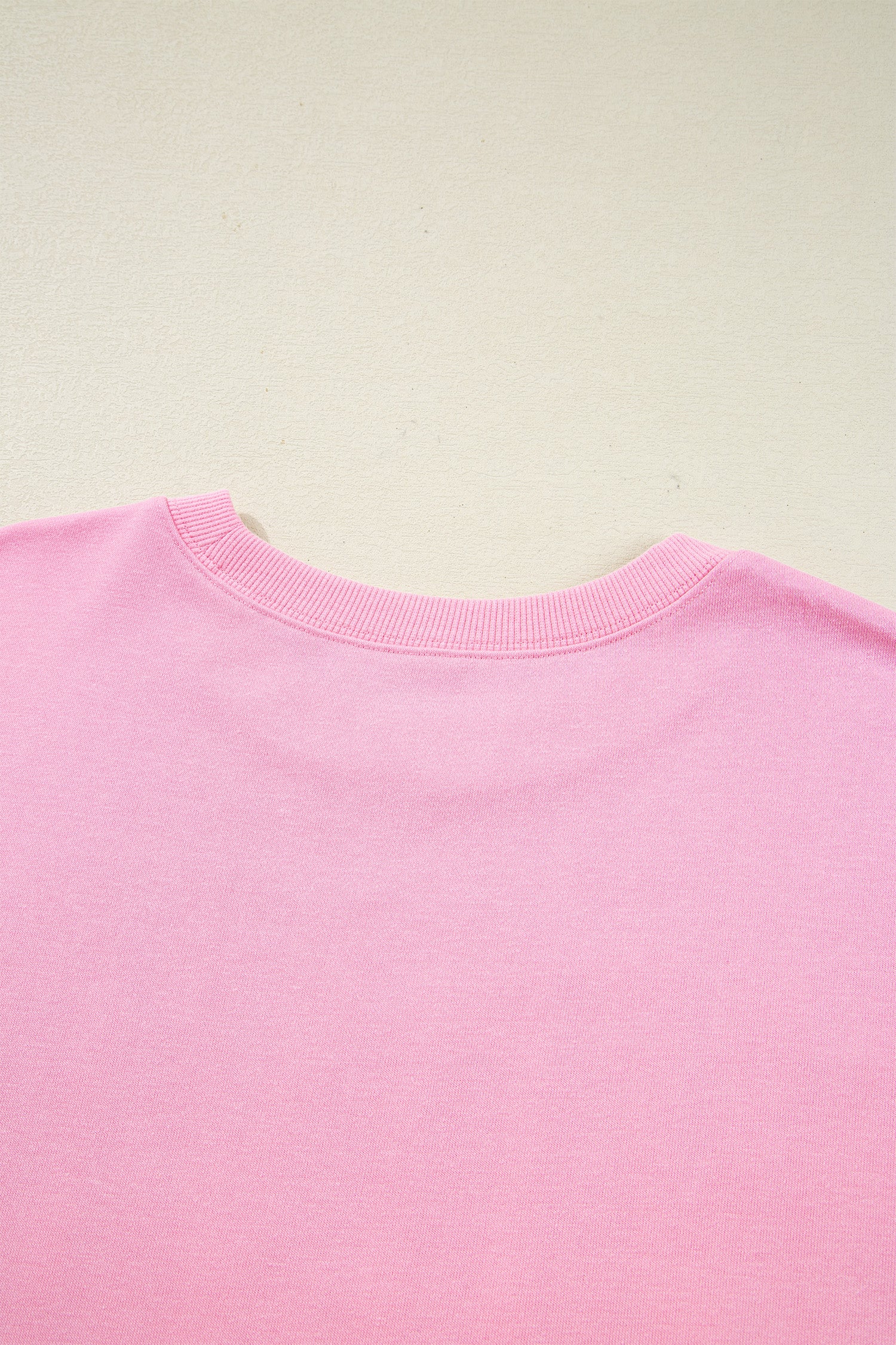 Pink bow sequin XOXO letter graphic baggy sweatshirt by Lavendar Lane Clothing, featuring exposed seams and casual blouse style.