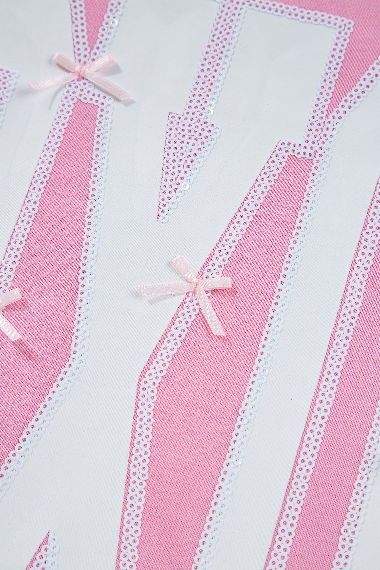 Pink sequin XOXO graphic sweatshirt with exposed seams and bow detail, casual blouse by Lavendar Lane Clothing.