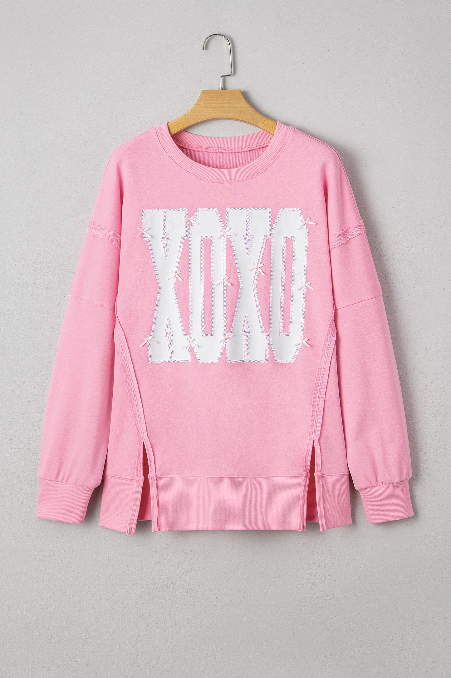 Pink sequin XOXO graphic baggy blouse with exposed seams from Lavendar Lane Clothing, featuring a bow detail and playful design.