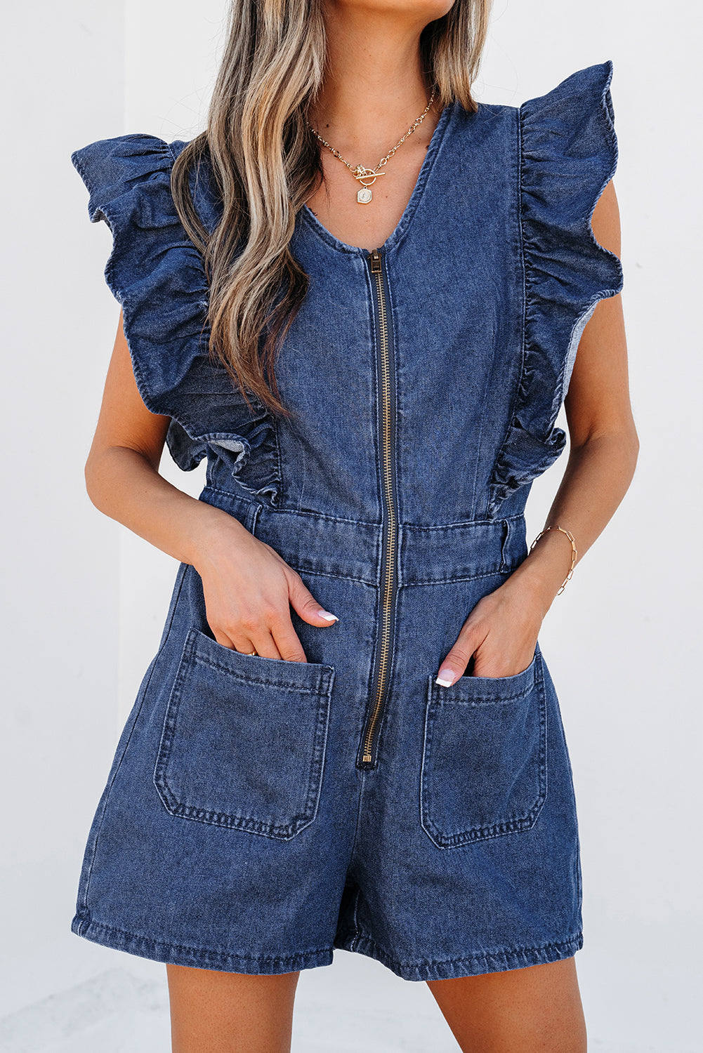 Lavendar Lane Clothing sail blue denim romper with ruffled front, zipper closure, and belt, perfect for casual summer wear.