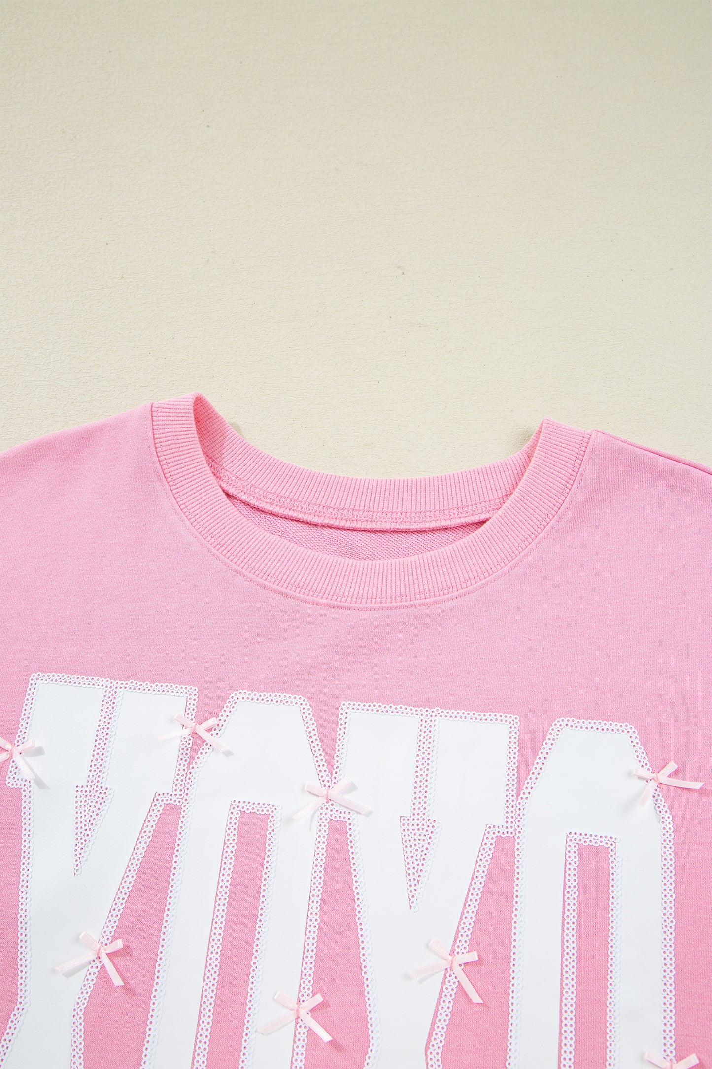 Pink sequin bow and XOXO graphic blouse by Lavendar Lane Clothing featuring exposed seams and a baggy fit.