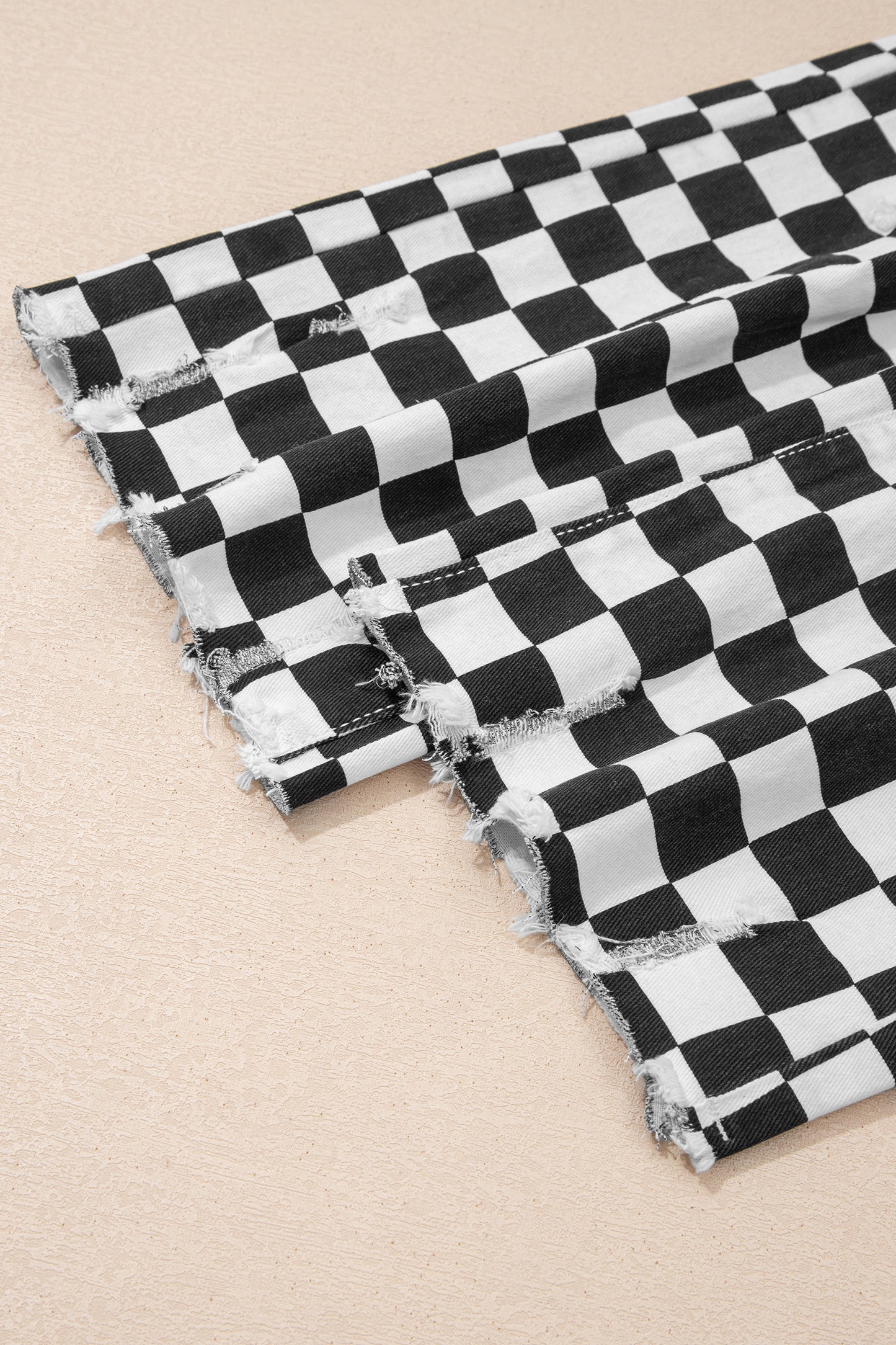 Black checkerboard print distressed raw edge cropped jeans by Lavendar Lane Clothing, featuring holes and a casual fit.