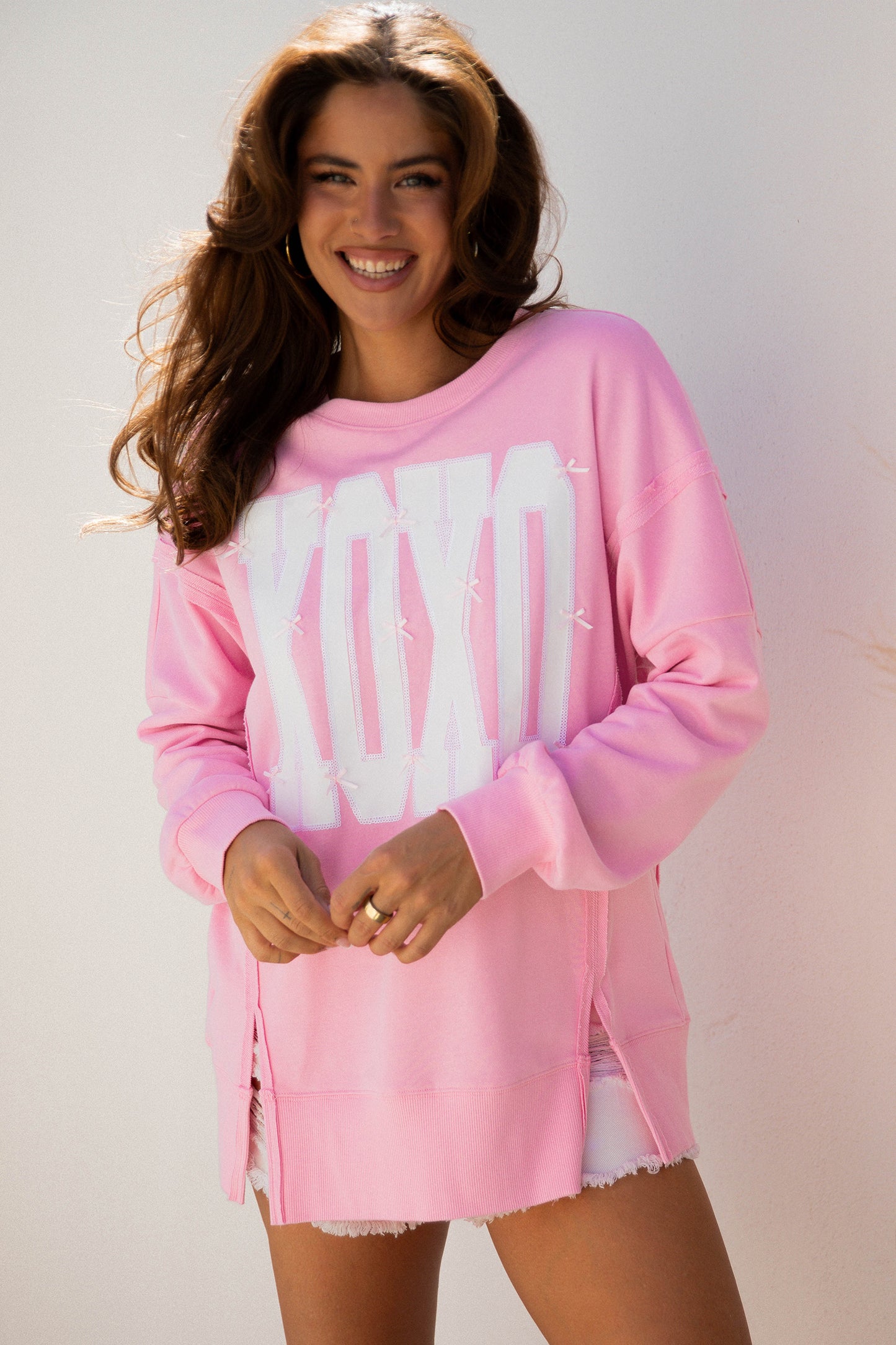 Pink bow sequin XOXO graphic baggy sweatshirt featuring exposed seams from Lavendar Lane Clothing.