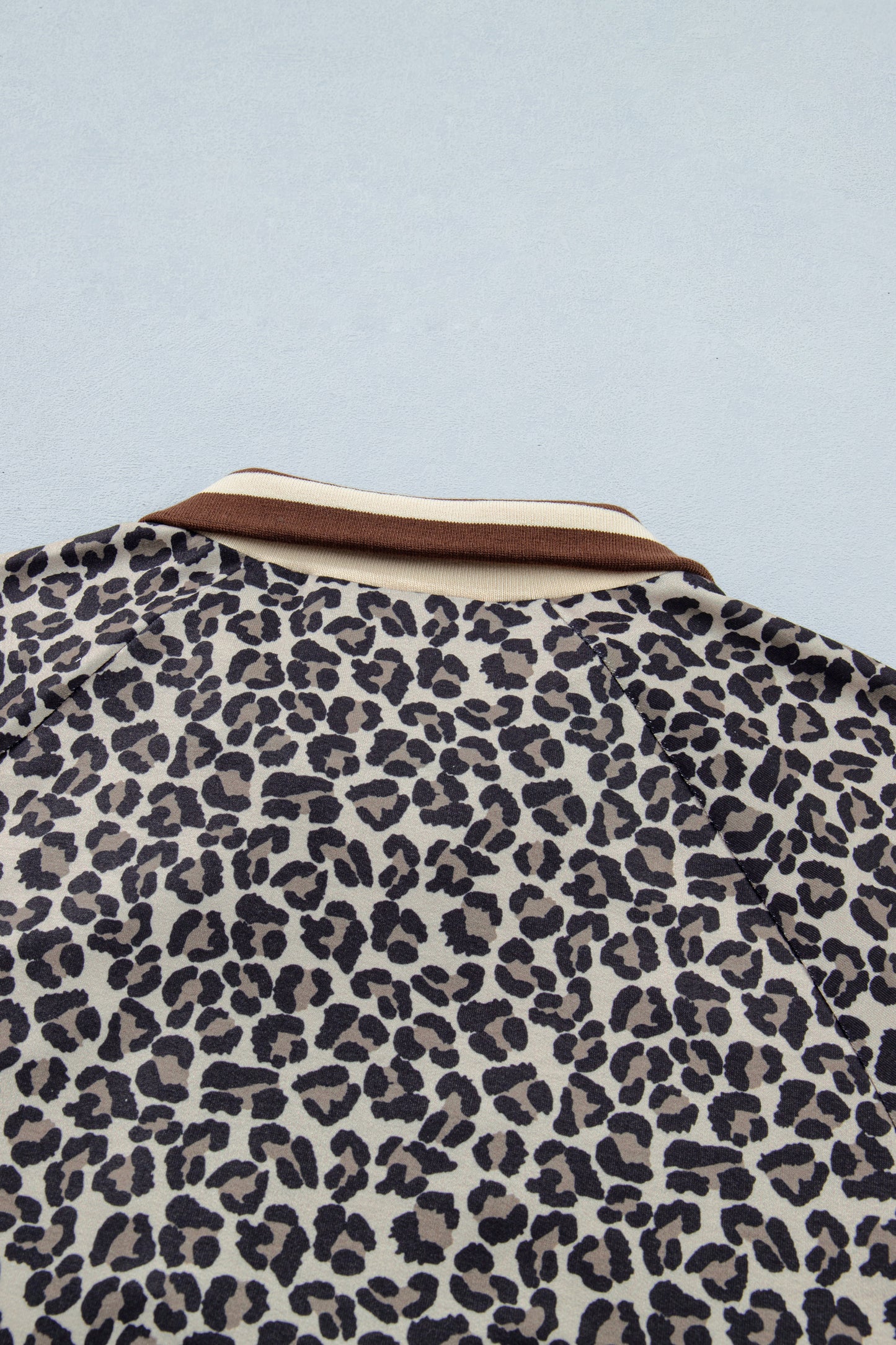 Lavendar Lane khaki leopard print short sleeve top with striped trim and patchwork details, featuring a half zip closure.