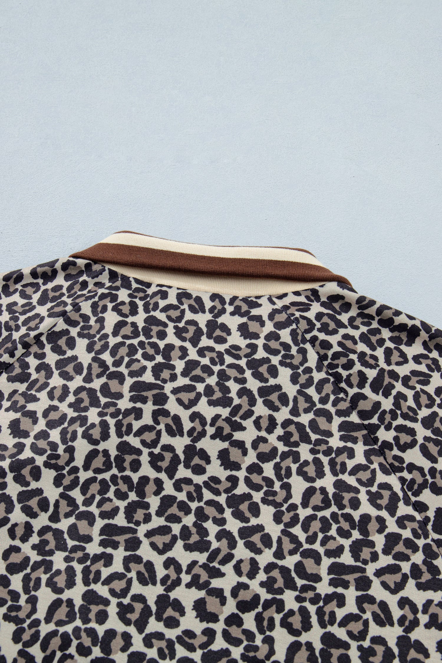 Lavendar Lane khaki leopard print short sleeve top with striped trim and patchwork details, featuring a half zip closure.