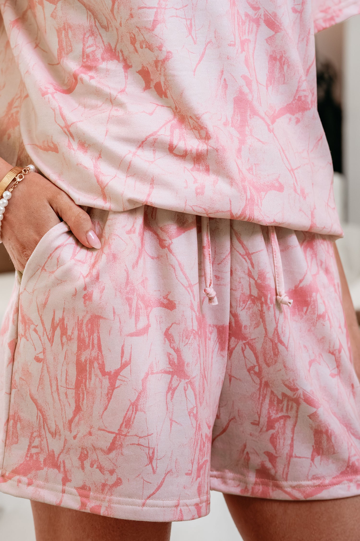 Pink abstract print V-neck loose tee with drawstring shorts, lavender lane two-piece set, casual summer outfit shown in the image.